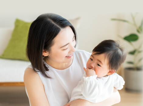 女性が室内で赤ちゃんを抱っこして微笑んでいる写真