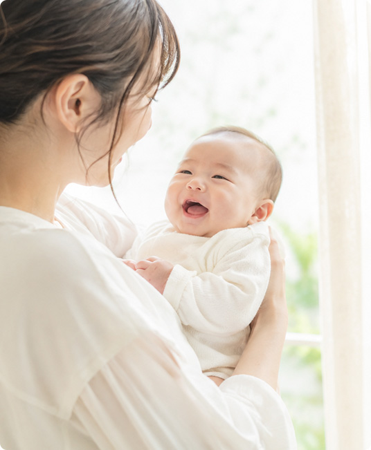 母親に抱っこされて笑顔のあかちゃん