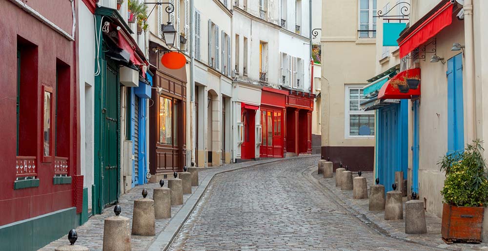 フランスの街並みを写した写真。赤や緑、青などカラフルな外壁やドアが左右に並んでいる