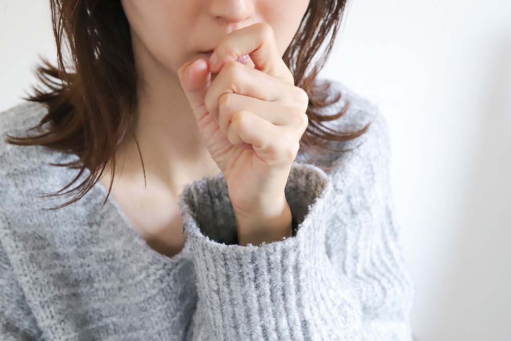 喉を押さえて咳き込む女性。長年ペットを飼っていても突然アレルギーを発症するケースの説明画像。