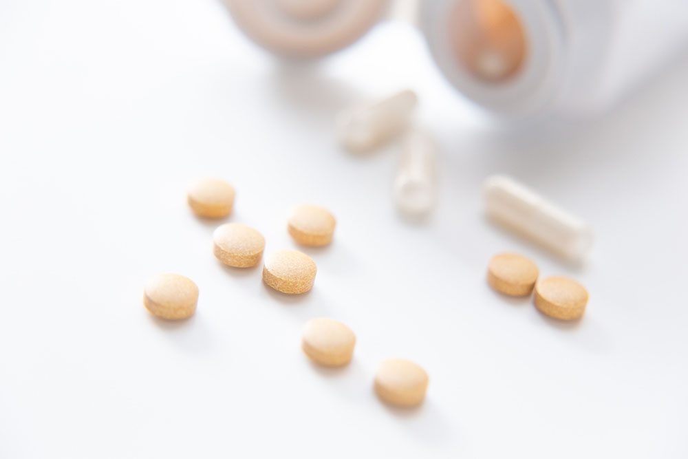 瓶から出したカプセルと錠剤。重症アレルギー治療に応用される生物学的製剤の研究イメージ。