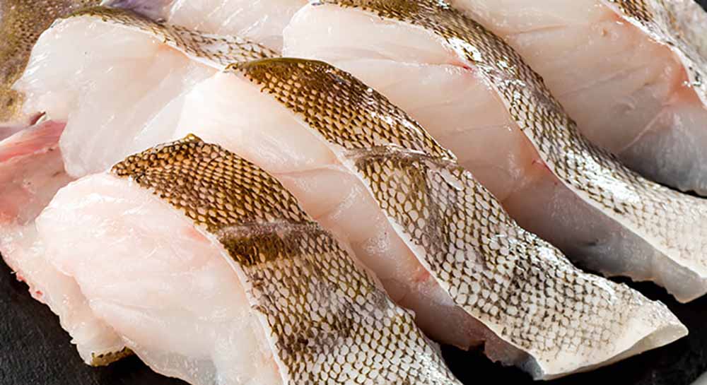 黒いお皿の上に4切れほどの白身魚の切り身が置かれた画像