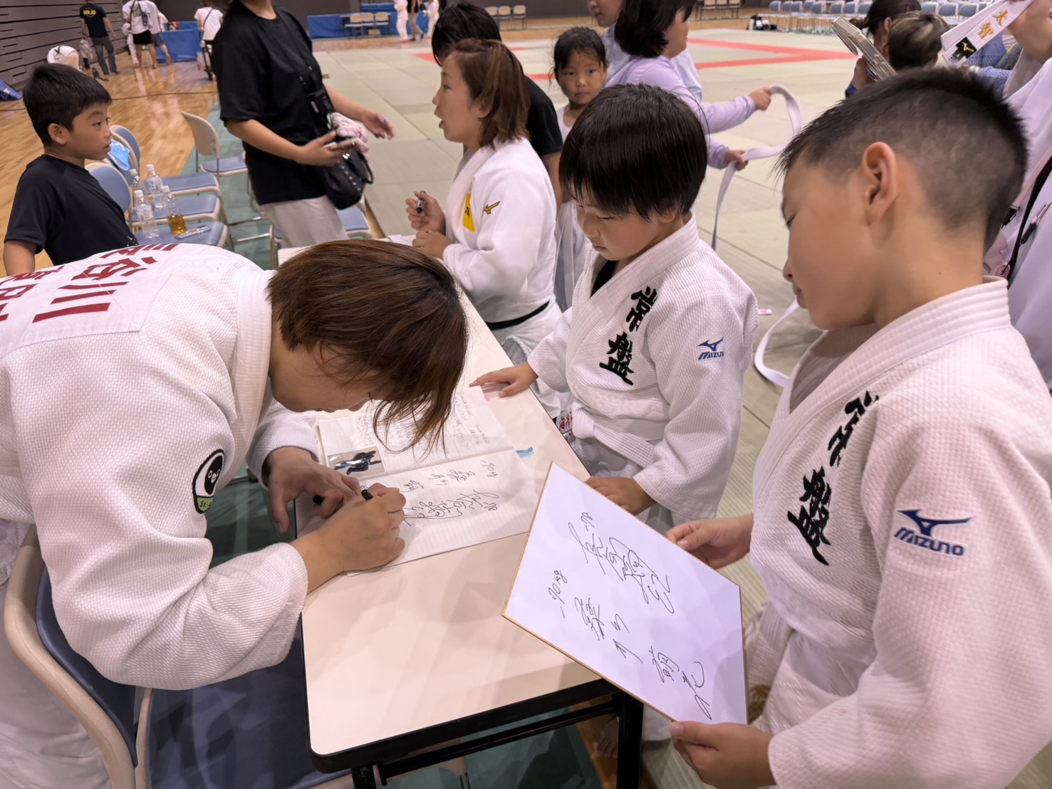 憧れの先生のサインを両手で受け取る子ども