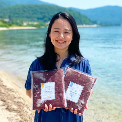 琵琶湖をバックにhugboxの商品を両手に持つhugboxの社長