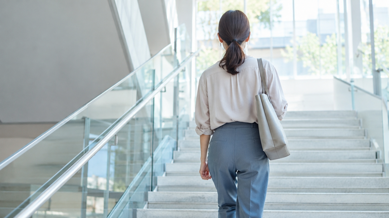明るい屋内の階段を上る女性の後ろ姿