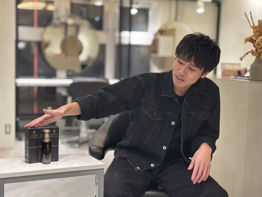 サロンで、LUJUの瓶と箱を前に話す三浦カイさん
