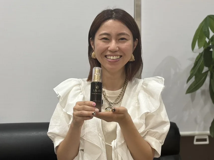 LUJUの瓶を手にほほ笑む、横内ありささん