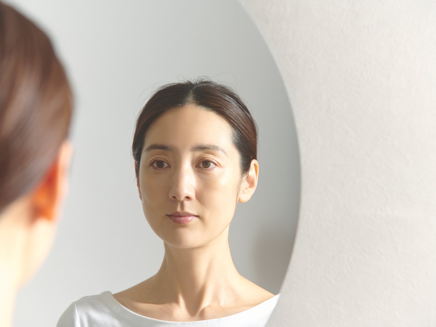 鏡に映る自分の肌を見つめる女性