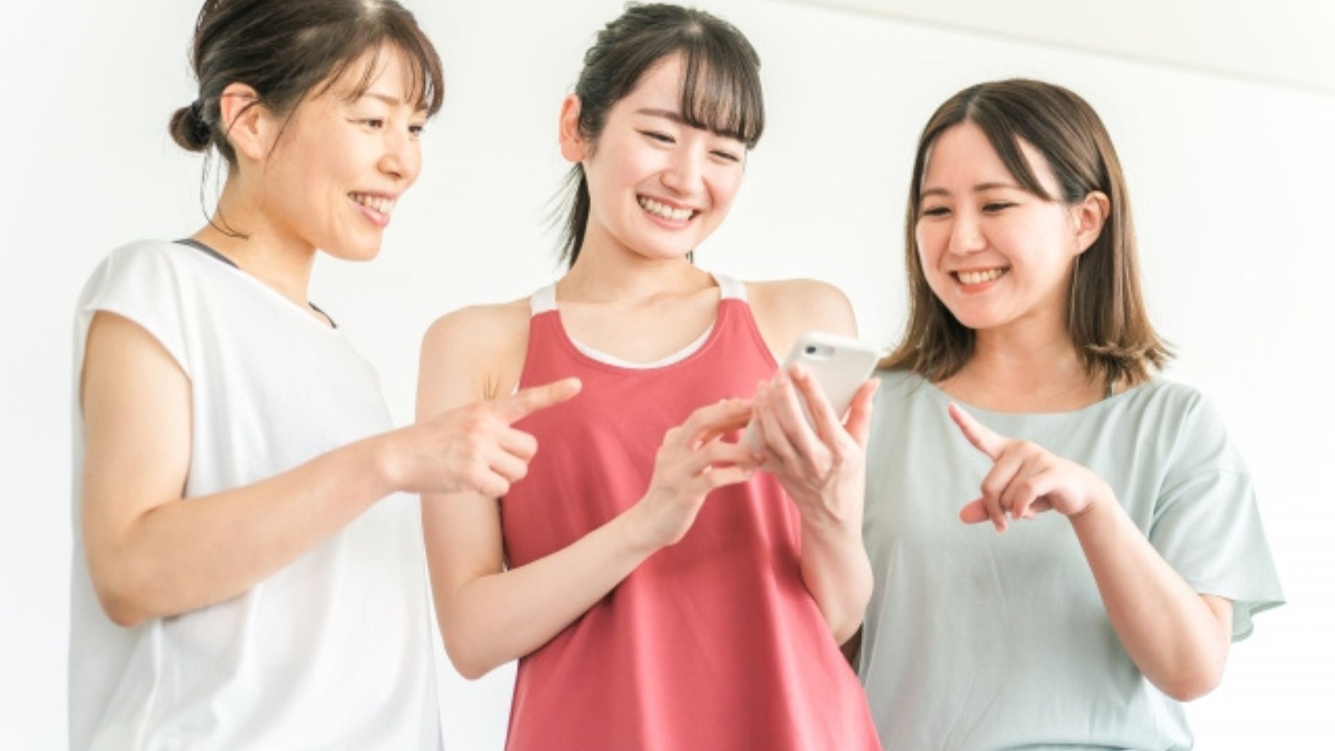 ジムでスマホを見ている3人の女性