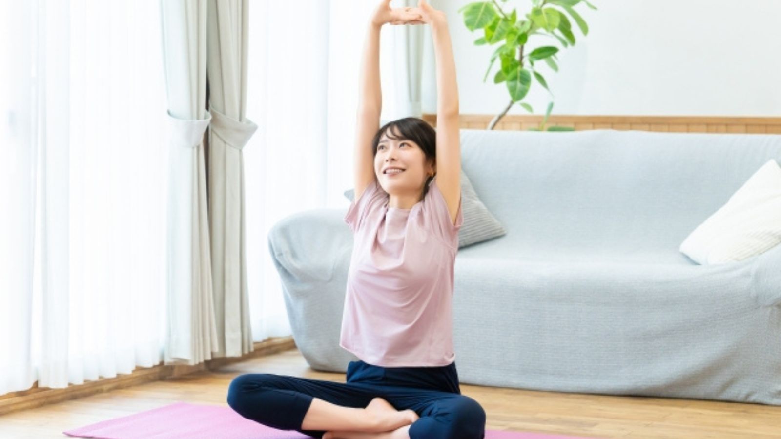 自宅のヨガマットの上でストレッチしている女性