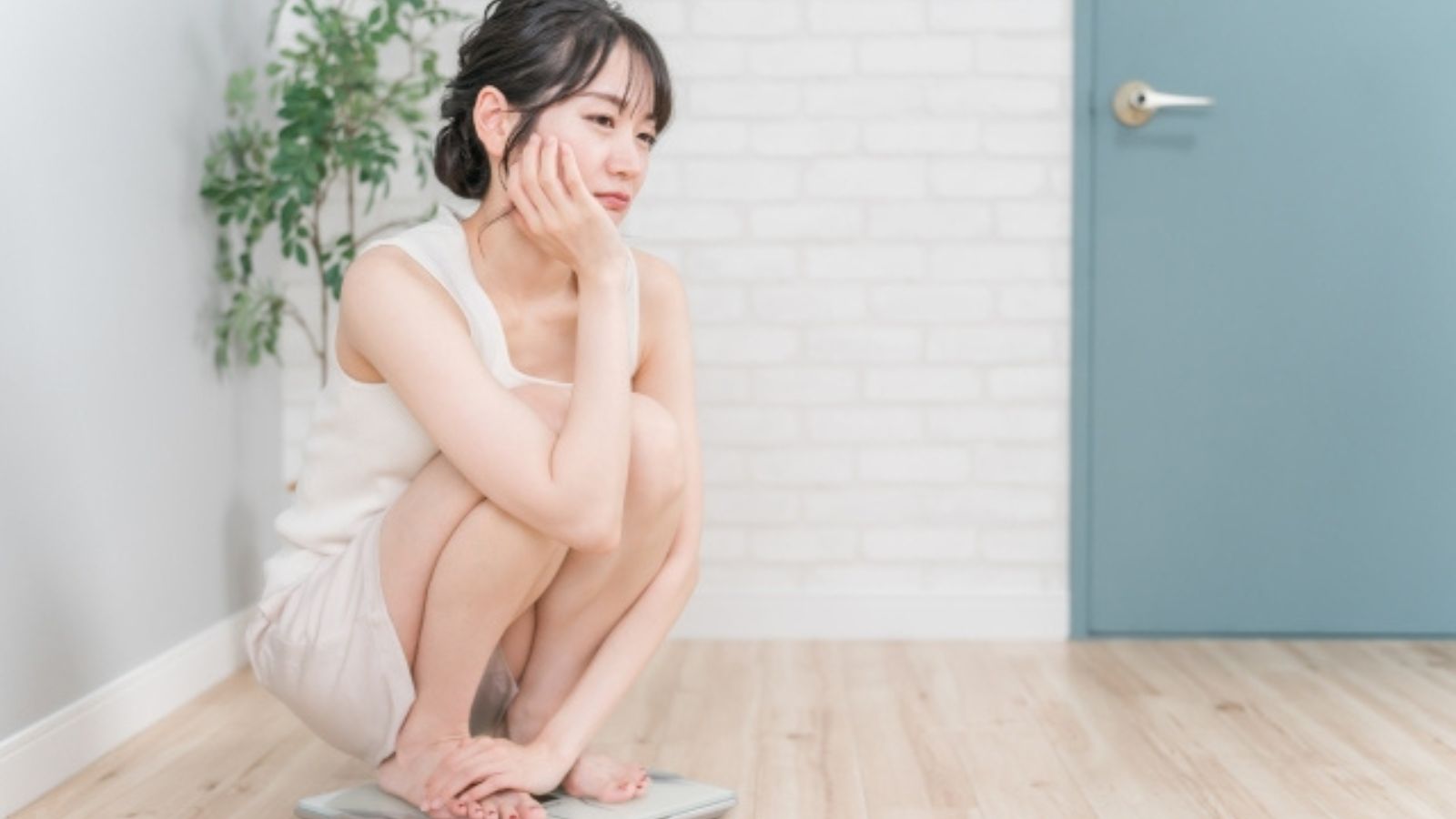 体重計に乗りうなだれている女性