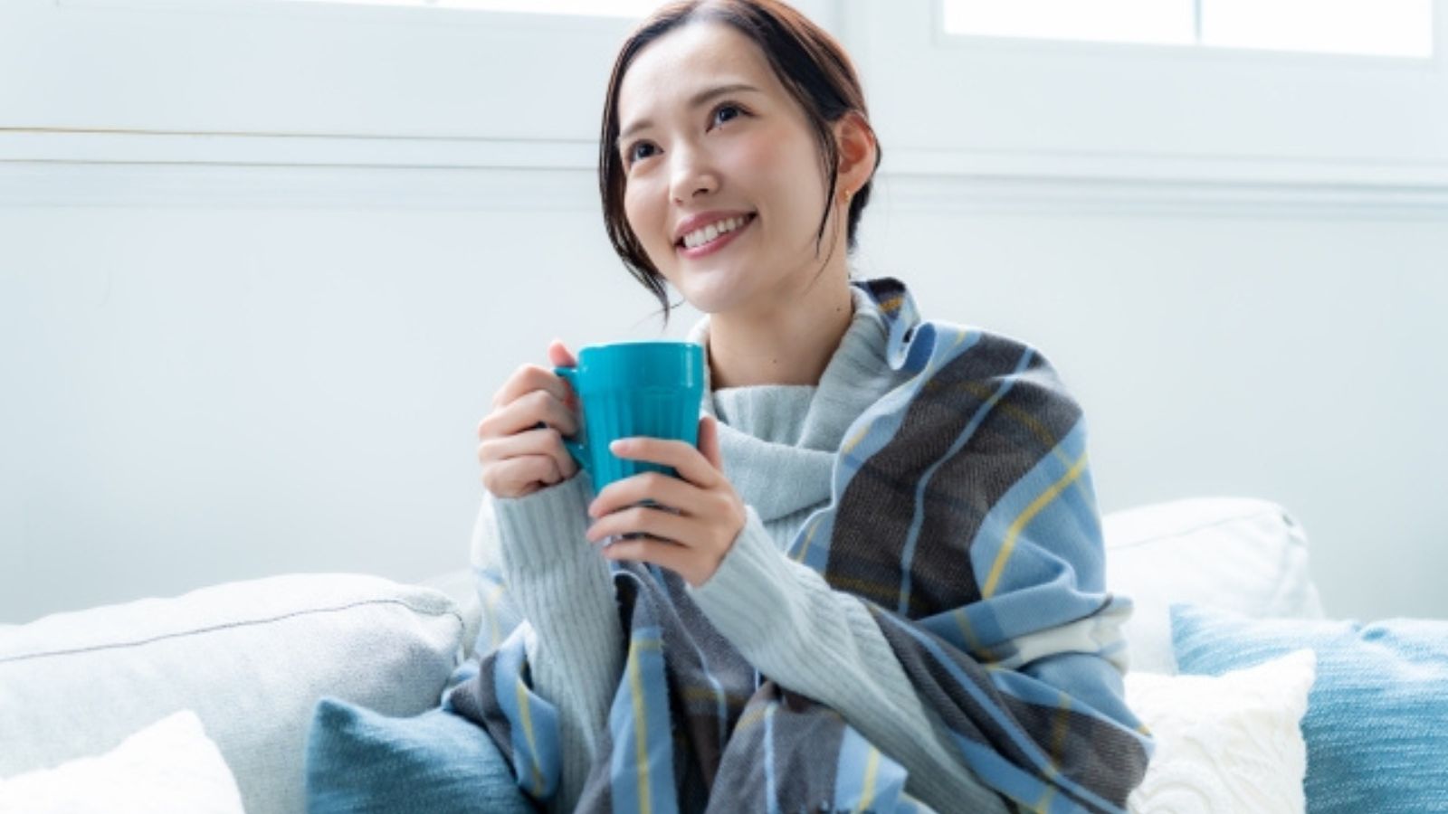 温かい飲み物やストールで身体を温めている女性