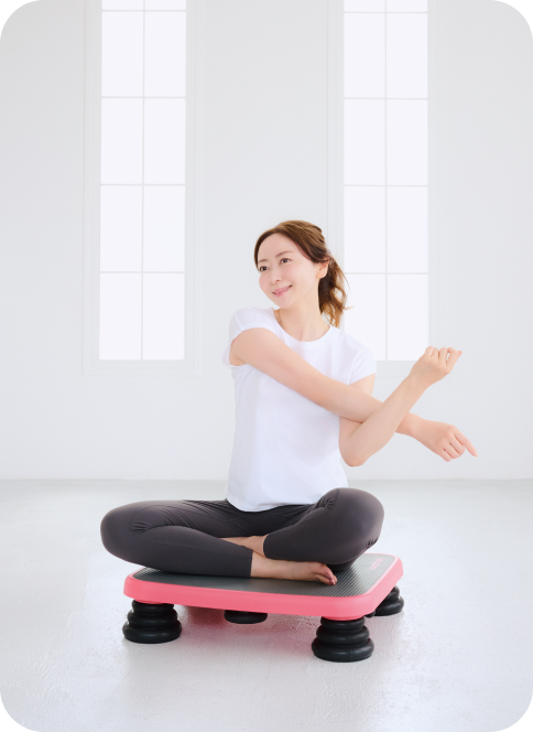 ジョグボードに座ってストレッチをする女性
