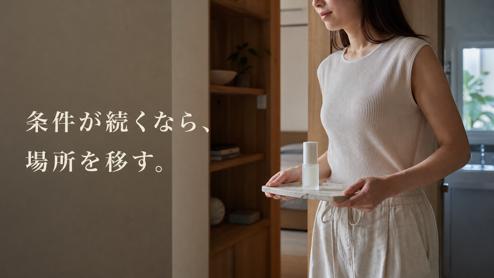 女性が無地美容液ボトルを石のトレイごと洗面所から室内棚へ運ぶ場面