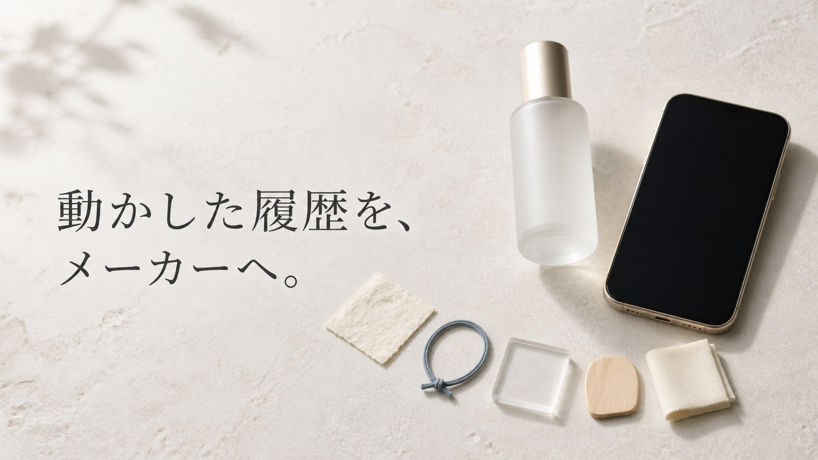 淡い石のテーブルに無地ボトル、画面の消えたスマートフォン、五つの異素材札を並べた真上からの編集静物